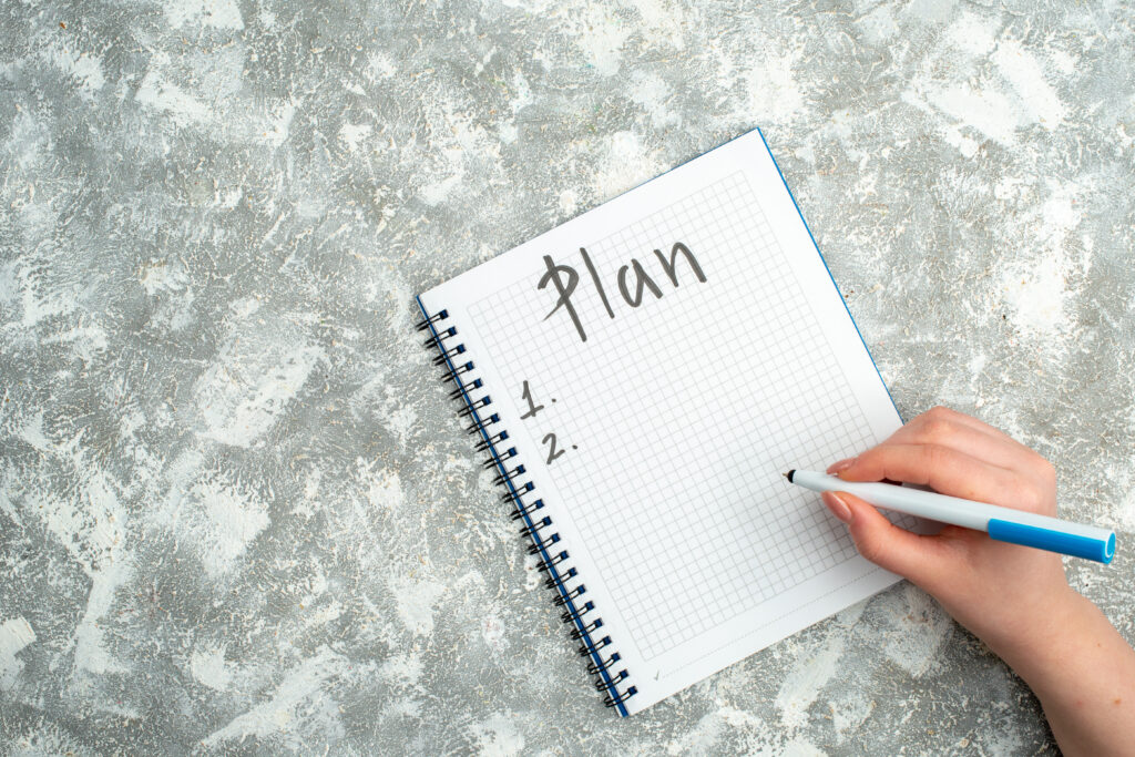 overhead-view-hand-writing-spiral-notebook-gray-background